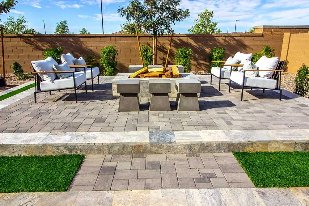 hardscaping-service-page-1 Modern outdoor living space featuring a paver patio with sleek seating and a central fire pit, surrounded by lush greenery and artificial grass, showcasing low maintenance landscaping ideal for Las Vegas landscaping needs.| Sun Valley Landscape Las Vegas