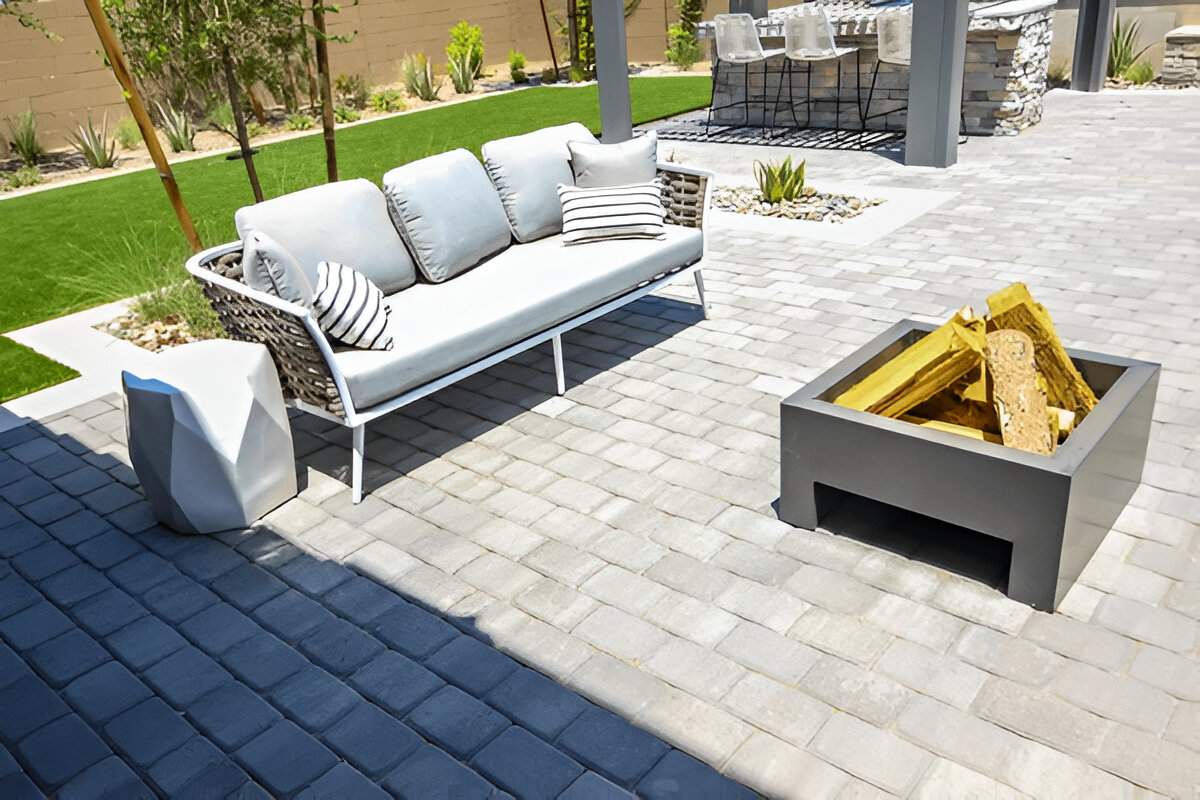 Modern patio with concrete pavers, sofa, and fire pit in a Las Vegas backyard by Sun Valley Landscaping company.