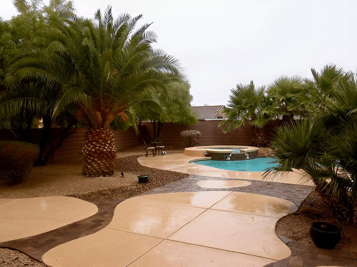 Palm trees and curved patio with pool in Las Vegas backyard designed by Sun Valley Landscaping company.