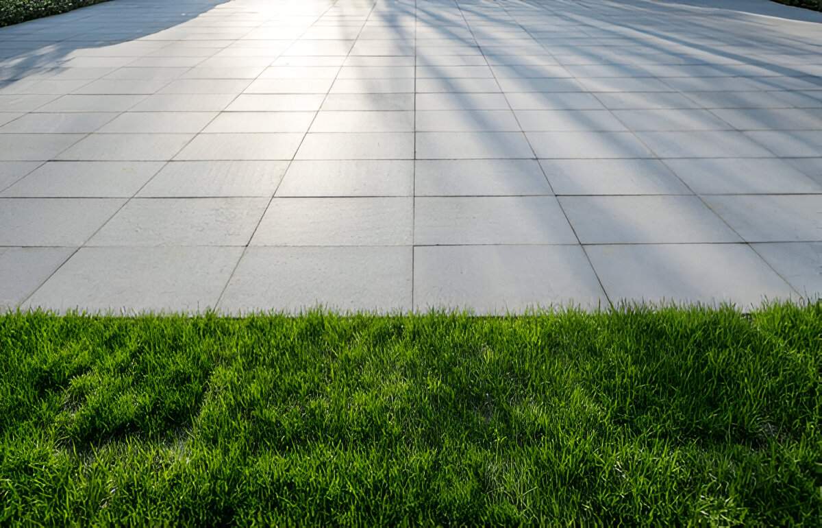 Modern patio with large square concrete pavers bordered by lush green grass, installed by Sun Valley Landscaping Las Vegas.