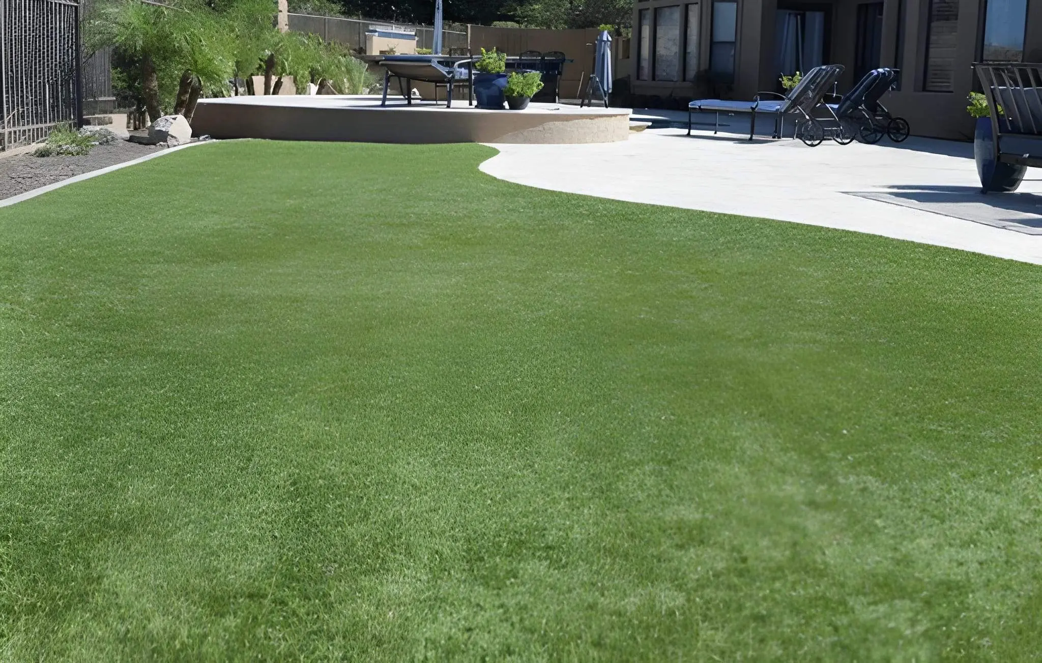 Artificial Turf vs. Natural Grass in Las Vegas Yards and Why Turf Wins in the Desert1 Wide backyard view with artificial turf and patio area designed for desert living by Sun Valley Landscaping in Las Vegas.