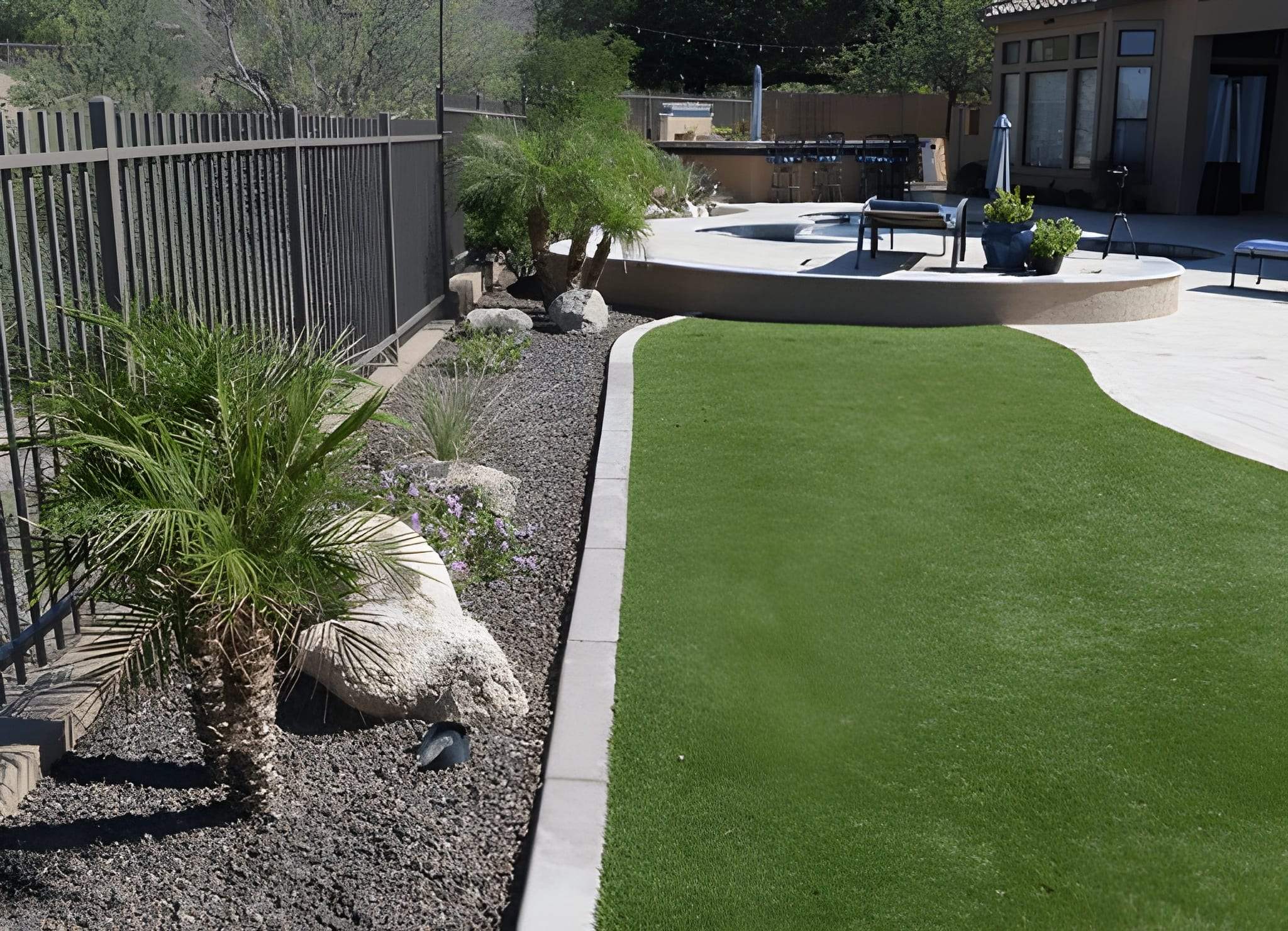 Artificial turf bordered by desert plants and pavers near a poolside patio installed by Sun Valley Landscaping in Las Vegas.