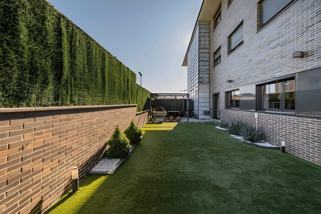 Artificial turf lawn beside a modern Las Vegas home with brick walls and privacy greenery by Sun Valley Landscaping.